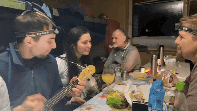 a man wearing a fenix headlamp is playing a guitar