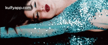 a woman in a blue sequined dress is laying on the ground ..
