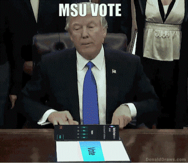 donald trump sitting at a desk with a sign that says msu vote on it