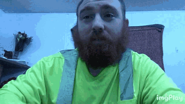 a man with a beard is wearing a neon green shirt and suspenders with imgplay written on the bottom