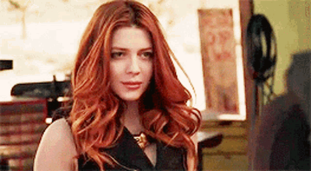 a woman with long red hair is wearing a black top