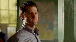 a man in a blue shirt and tie is standing in front of a map in a room .
