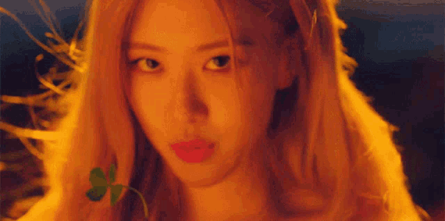 a close up of a woman 's face with a green clover in her hair .