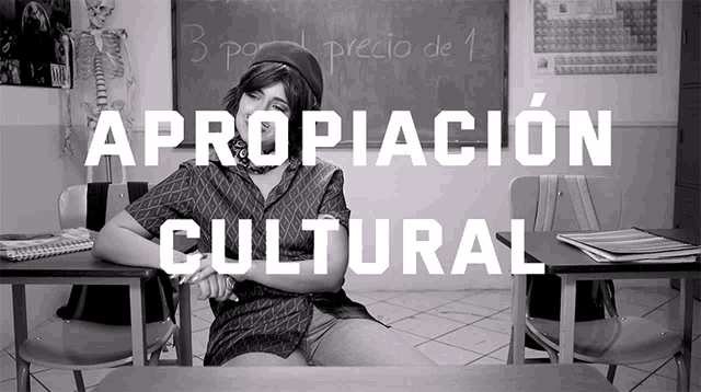 a woman sits at a desk in front of a blackboard with the words " apropiacion cultural " on it