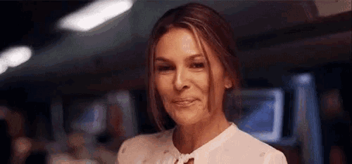 a woman in a white shirt is smiling at the camera .