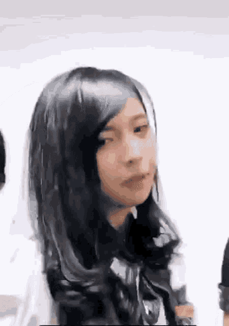 a young woman with long black hair is making a funny face .