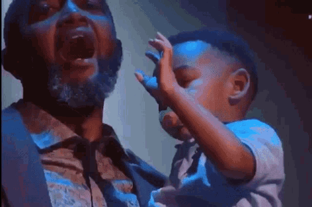 a man with a beard is holding a baby with a pacifier in his hand .
