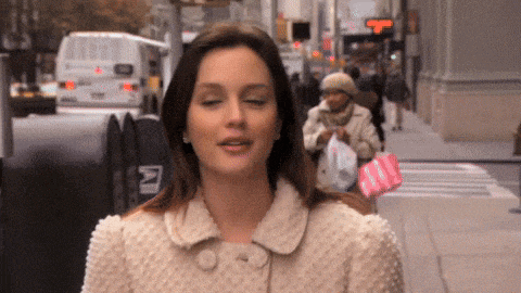 a woman walking down a street with a mailbox that says n
