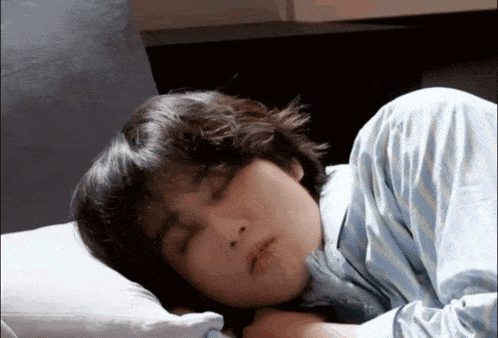 a person sleeping on a bed with their eyes closed and their head on a pillow