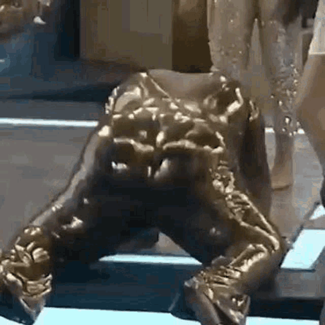 a statue of a man in a gold suit is kneeling down on the floor .
