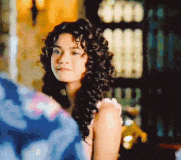 a woman with curly hair is looking at the camera in a blurry photo