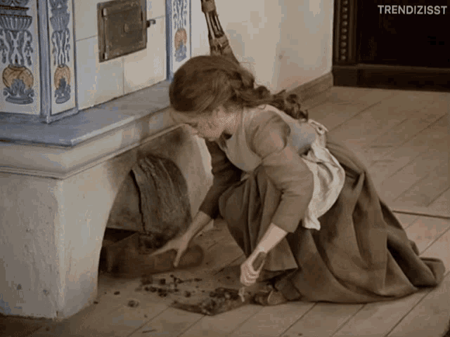 a woman in a brown dress is cleaning the floor with a shovel and the words trendizisst on the bottom