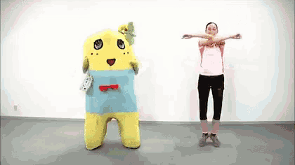 a woman is standing next to a yellow and blue mascot .