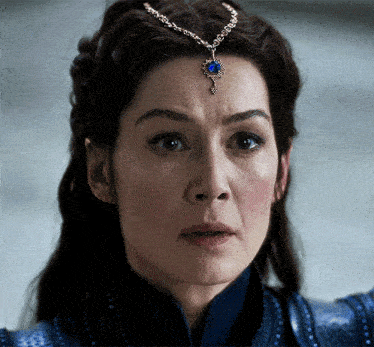 a close up of a woman 's face with a blue pendant on her forehead