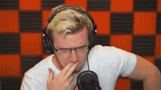 a man wearing headphones and glasses covering his mouth