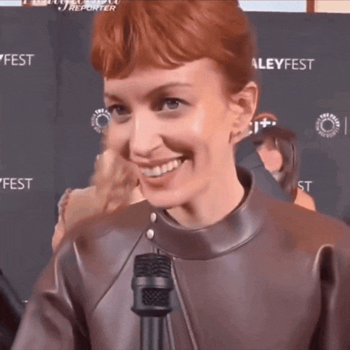 a woman with red hair is smiling while holding a microphone
