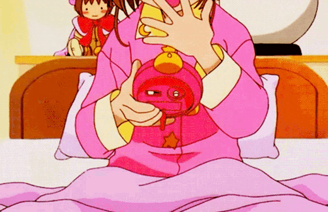 a girl in a pink pajamas is sitting on a bed holding a pink clock