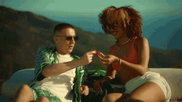 a man and a woman are sitting on a boat and the woman is wearing a red bikini top