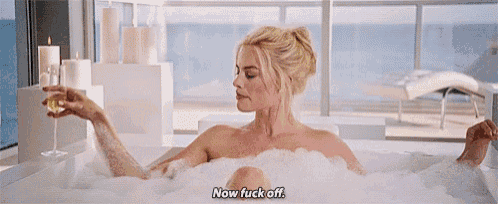 a naked woman is sitting in a bathtub with a glass of wine .