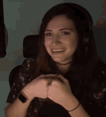 a woman wearing headphones and a choker smiles in front of a microphone