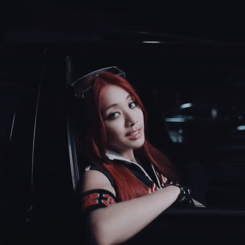 a woman with red hair is wearing sunglasses and a black shirt that says ' x ' on it