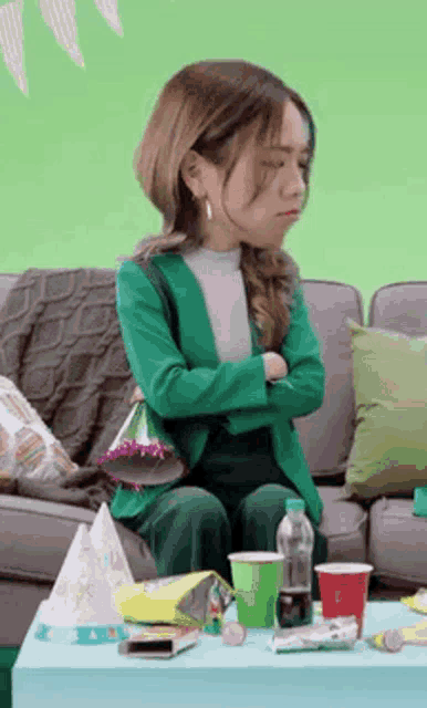 a woman in a green jacket is sitting on a couch