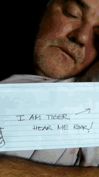 a man is holding a piece of paper that says i am tiger roar hear me