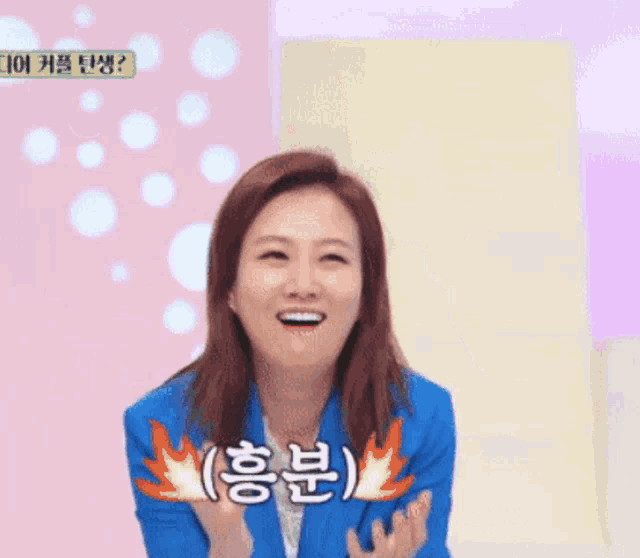 a woman in a blue jacket is smiling in front of a sign that says ' fire '