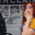 a woman covering her mouth with her hand in front of a sign that says ' inclair ' on it
