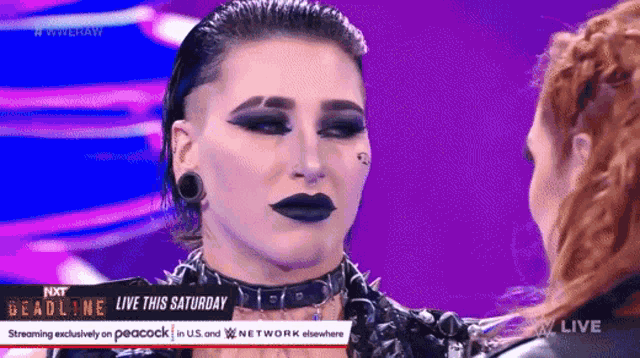 two women are standing next to each other on a stage and one of them is wearing black lipstick .