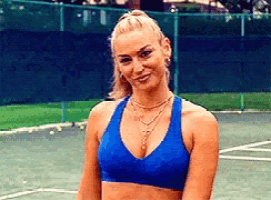 a woman in a blue sports bra stands on a tennis court .