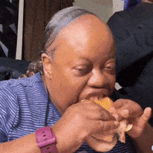 a woman wearing a pink watch is eating a hamburger