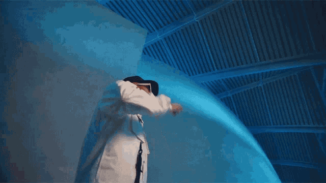 a man in a white coat is standing in front of a large blue object