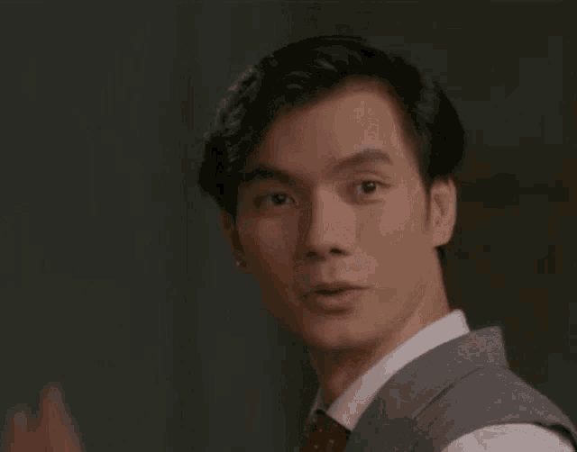 a young man in a suit and tie is waving his hand