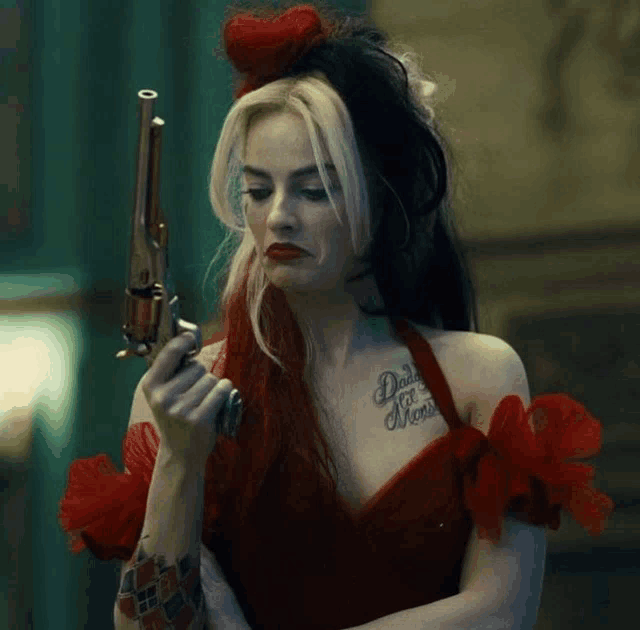 a woman in a red dress is holding a gun and has daddy 's monster tattoo on her chest
