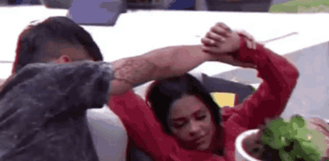 a man and a woman are sitting on a couch holding hands . the woman is wearing a red sweater .