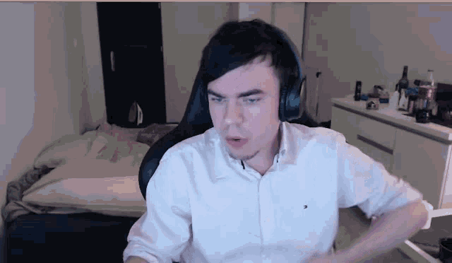 a man wearing headphones and a white shirt is sitting in a room