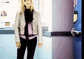a woman in a white jacket is standing in a hallway next to a blue door