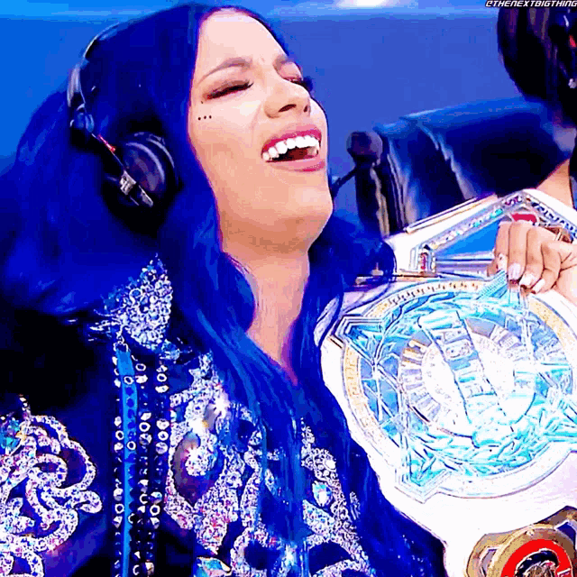 a woman with blue hair is holding a world heavyweight championship belt