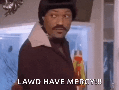a man in a suit and hat is standing in front of a refrigerator and saying lawd have mercy !