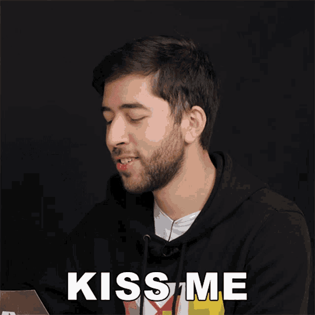 a man with a beard says kiss me in front of a black background