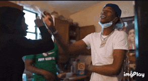 a man wearing a mask is giving another man a high five in a kitchen