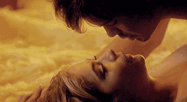 a man and a woman are kissing in a bed