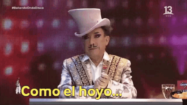 a man in a top hat says " como el hoyo " on a screen