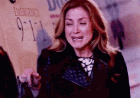 a woman is crying in front of a sign that says `` emergency '' .