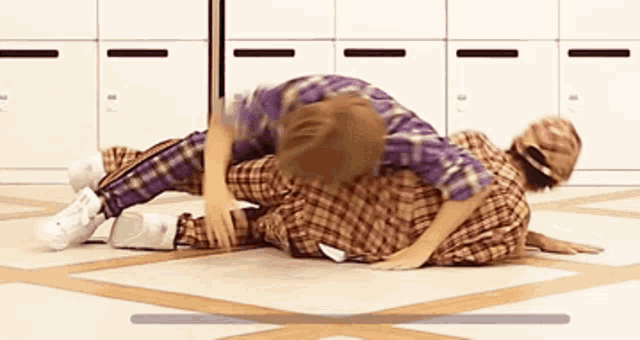 two people are laying on the floor in a room with lockers