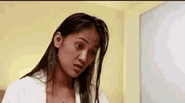a woman in a white robe is standing in front of a mirror looking at herself .