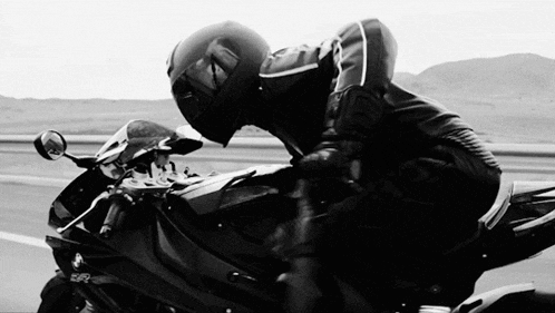 a man wearing a helmet is riding a motorcycle on a road