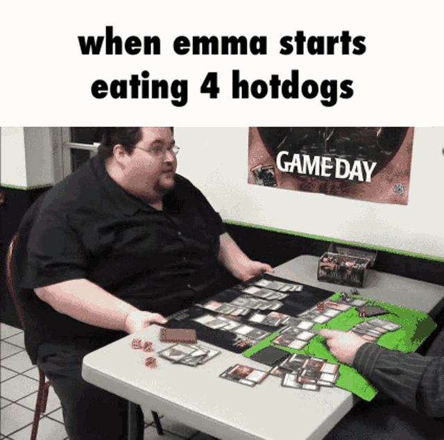 a man sits at a table playing a game with a game day poster on the wall behind him