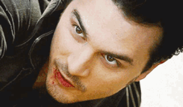a close up of a man 's face with blood on his lips